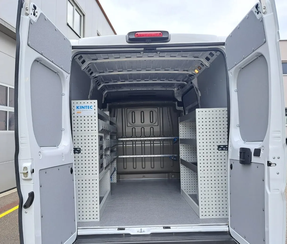 Fiat Ducato mit offenen Hecktüren, links und rechts Regale mit Lochwänden, Bodenplatte und Wandverkleidung