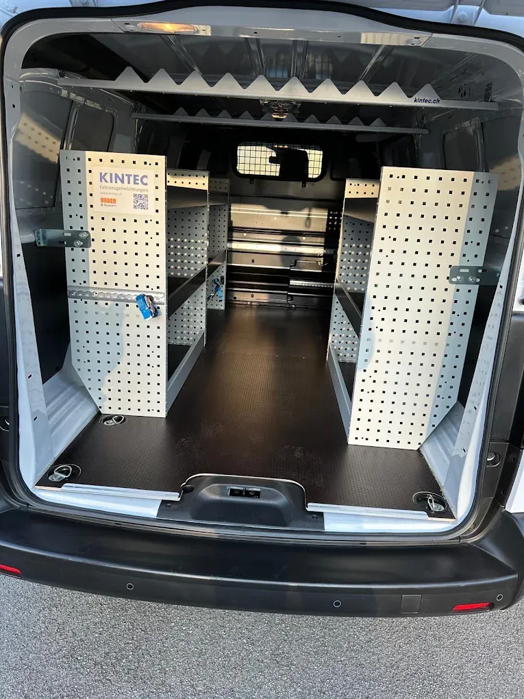 Blick durch die offenen Hecktüren auf ein frisch gereinigtes Regalsystem beidseitig im Laderaum