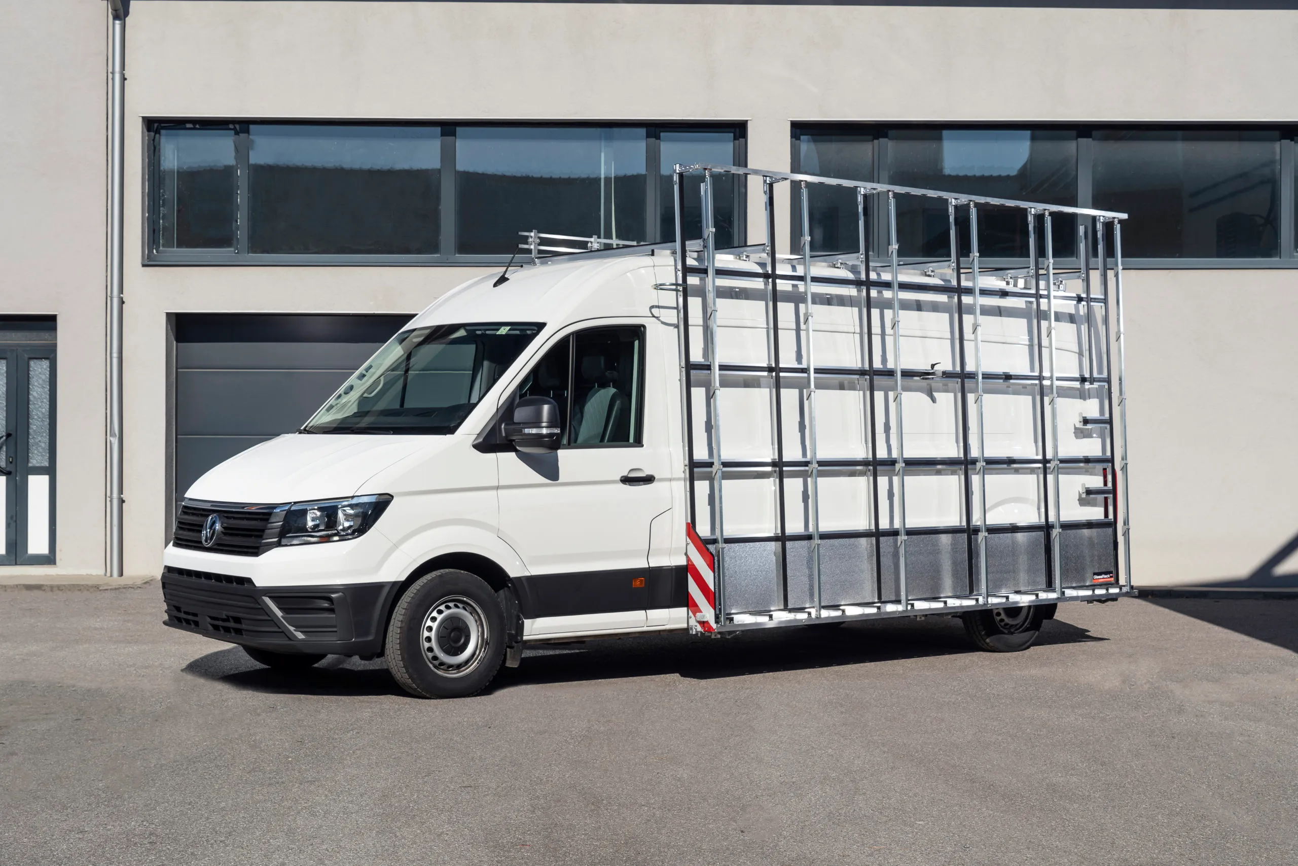 Weisser Transporter mit seitlich montiertem Aussenglasreff, Seitenansicht vor einer Werkhalle