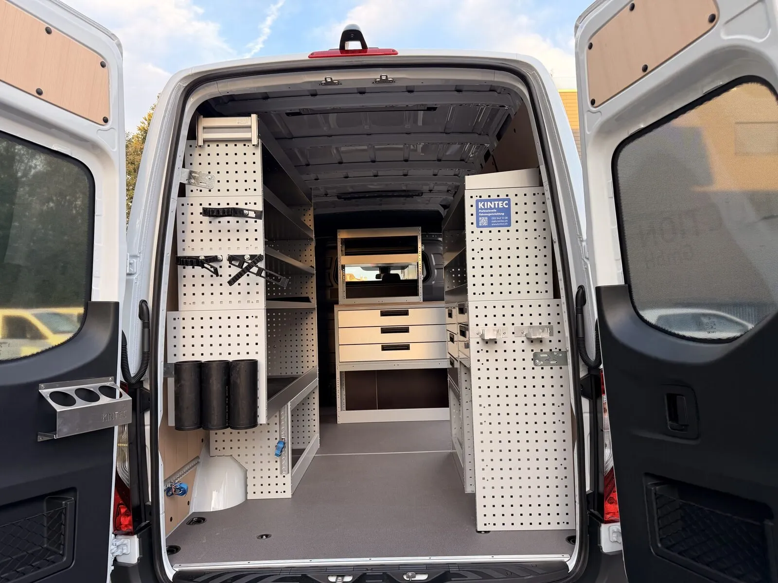 Mercedes Sprinter mit geöffneten Hecktüren: beidseitig Lochwände und Regale, an der Trennwand ein Schubladenblock