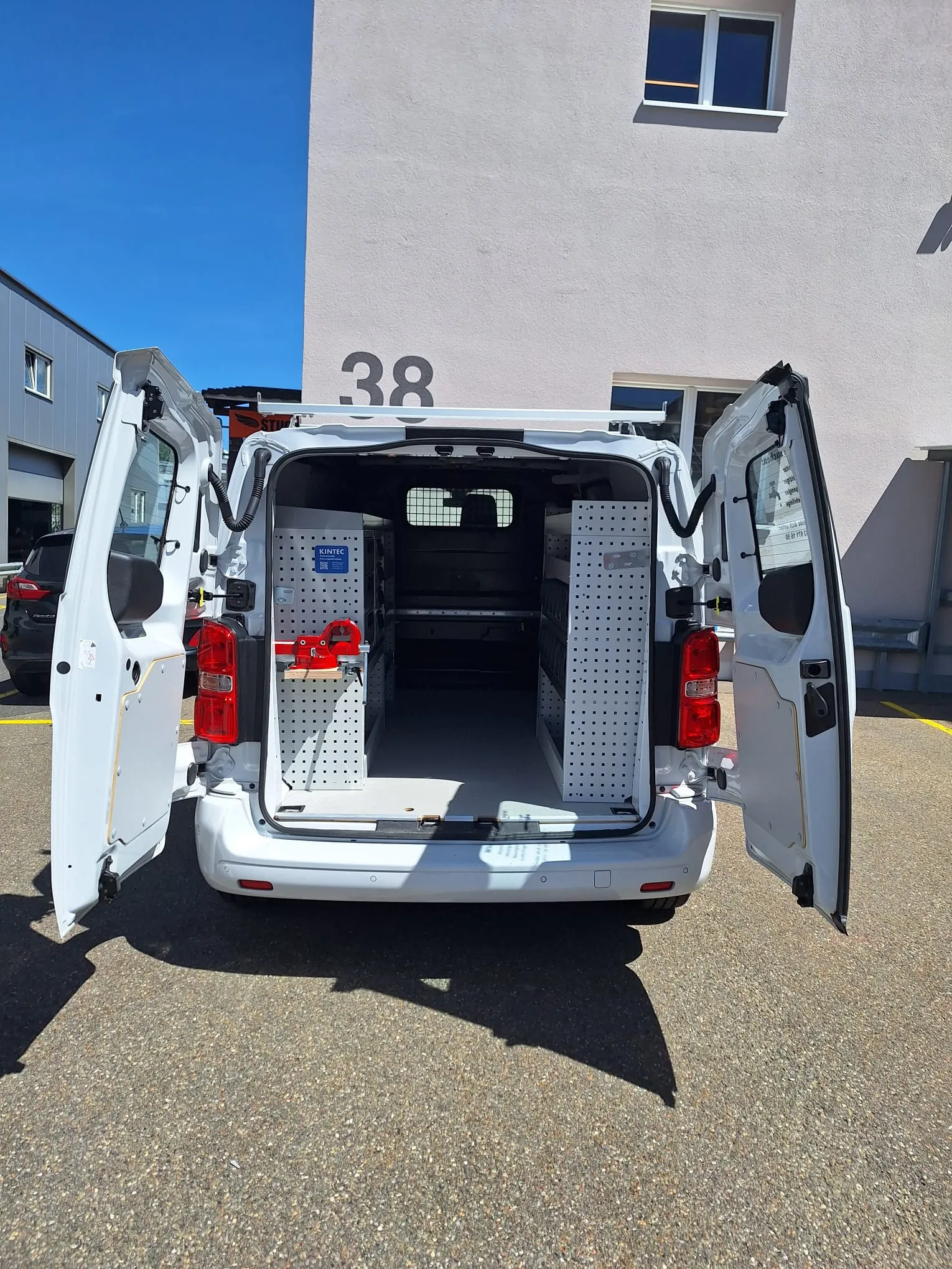 Transporter mit weit geöffneten Hecktüren, im Laderaum die fertig montierte Einrichtung