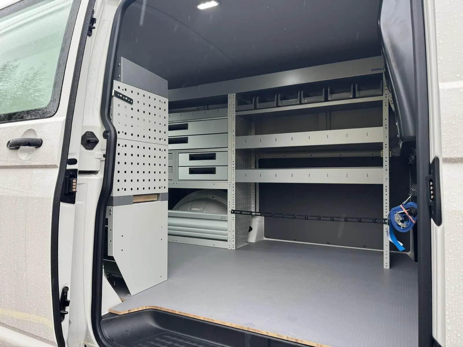 Blick durch die Schiebetür eines VW T6.1: Regalzeile mit Schubladen, Sortimentskästen und Fachböden